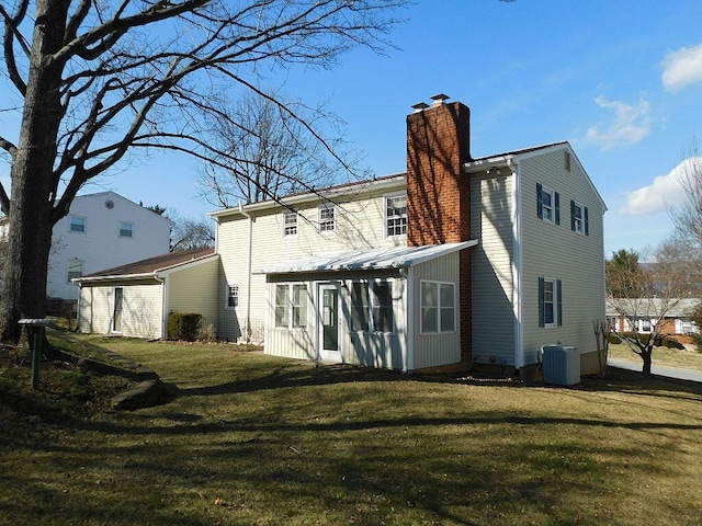 back of house with central AC unit and a lawn