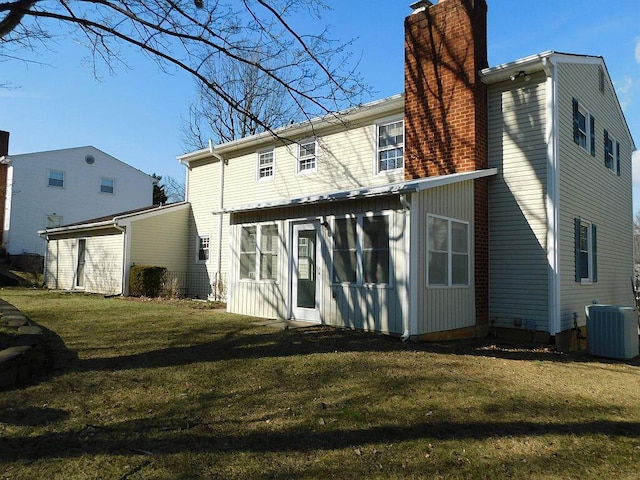 rear view of house featuring central AC unit and a lawn