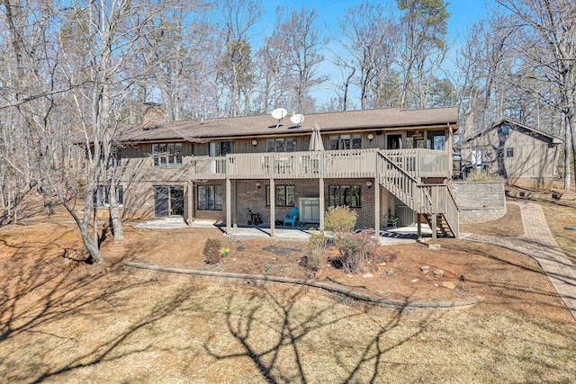 back of property featuring brick siding, stairway, a wooden deck, a chimney, and a patio area