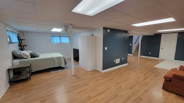 bedroom with a paneled ceiling and light hardwood / wood-style flooring