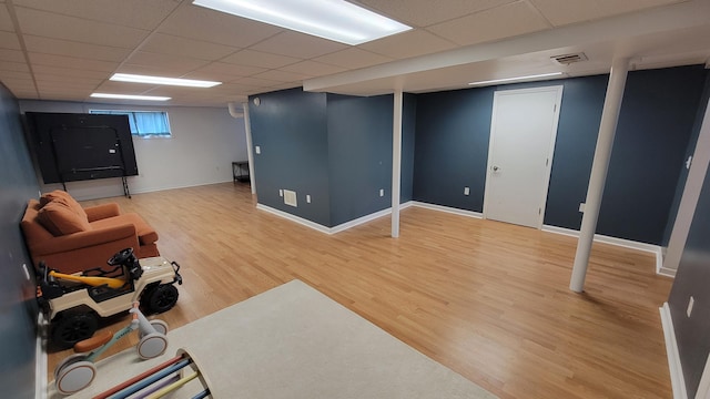 basement with a paneled ceiling and wood-type flooring