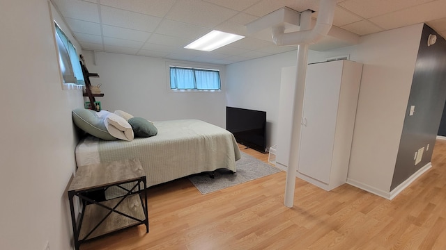 bedroom featuring a drop ceiling and light hardwood / wood-style flooring