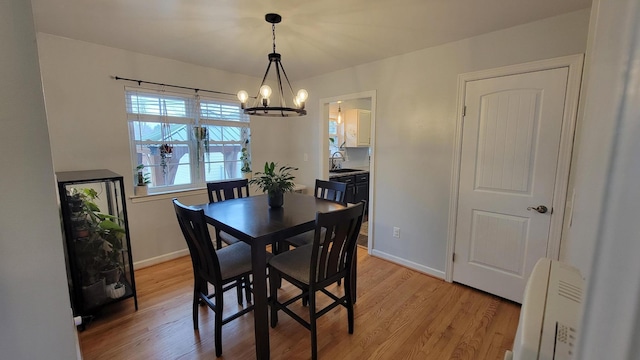 dining room featuring an inviting chandelier, sink, and light wood-type flooring