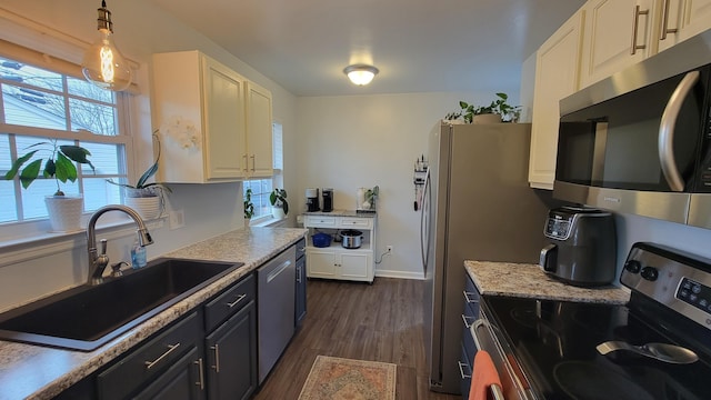 kitchen featuring sink, dark wood-type flooring, white cabinetry, stainless steel appliances, and decorative light fixtures