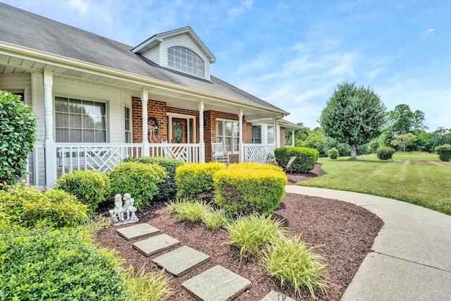 view of front facade with a front yard, a porch, and brick siding