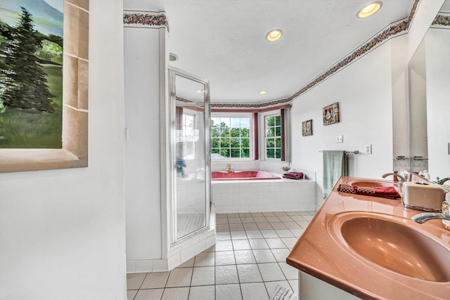 bathroom with a garden tub, a textured ceiling, a sink, and tile patterned floors