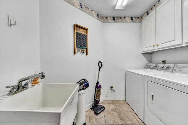 clothes washing area with light tile patterned floors, cabinet space, washing machine and dryer, a sink, and baseboards