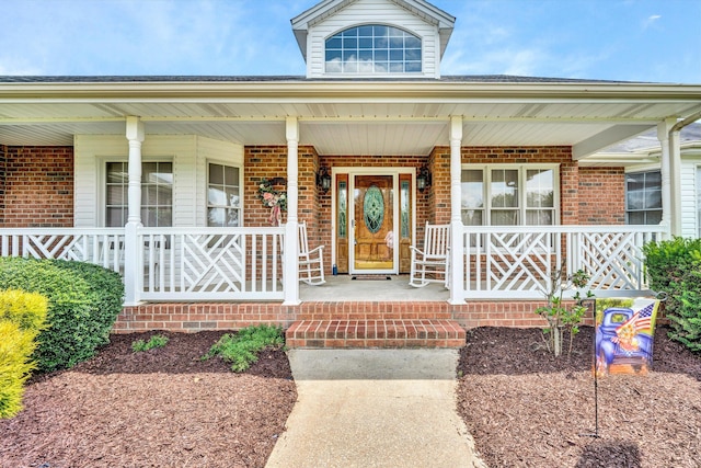 entrance to property with covered porch and brick siding