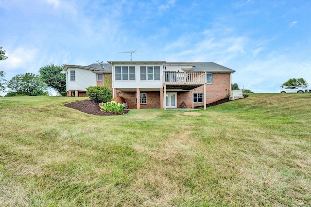 rear view of house featuring a deck, brick siding, and a lawn