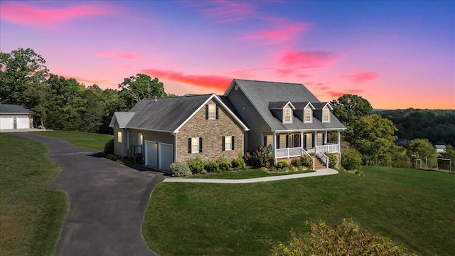 cape cod house featuring covered porch and a lawn