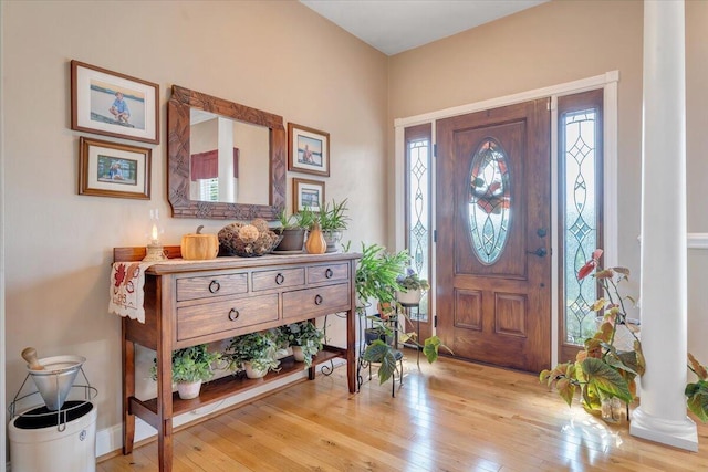 entrance foyer featuring ornate columns, plenty of natural light, and light hardwood / wood-style flooring