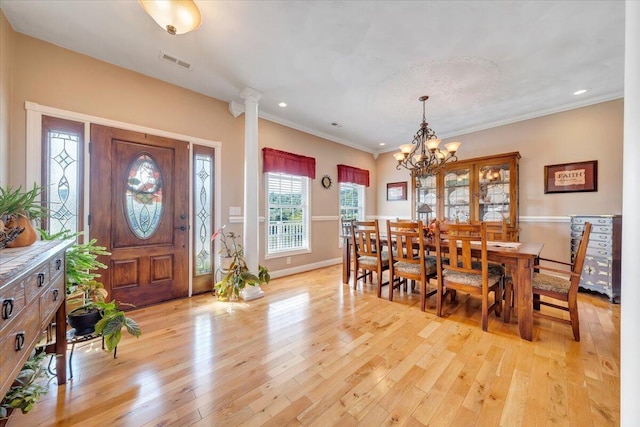 foyer with an inviting chandelier, ornamental molding, light hardwood / wood-style flooring, and ornate columns