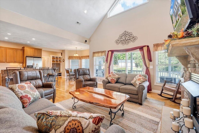 living room featuring high vaulted ceiling and light hardwood / wood-style floors