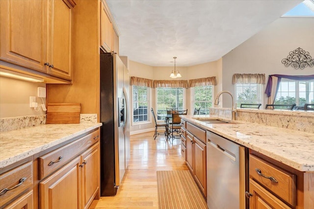 kitchen with pendant lighting, sink, light hardwood / wood-style flooring, stainless steel appliances, and light stone counters