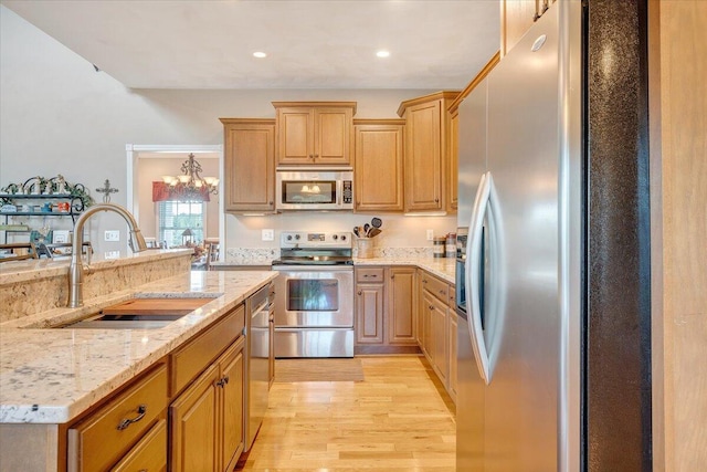 kitchen featuring light stone counters, appliances with stainless steel finishes, light hardwood / wood-style floors, and sink