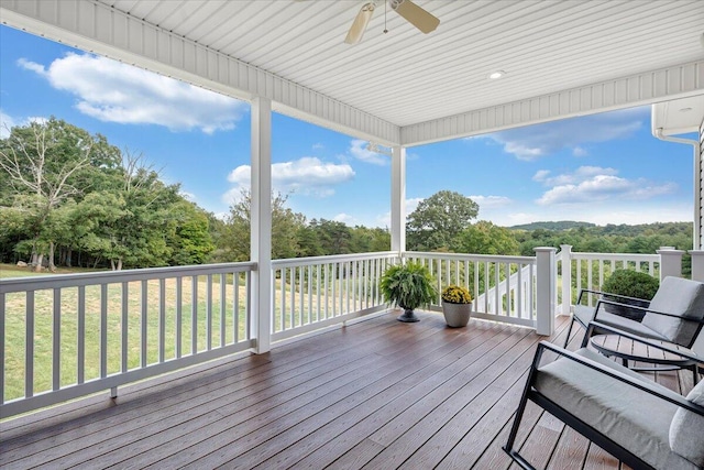 wooden terrace featuring ceiling fan, a wall mounted AC, and a lawn