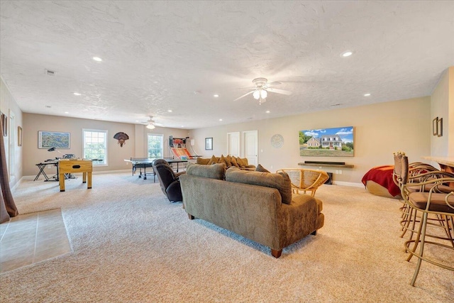 living room featuring ceiling fan, light colored carpet, and a textured ceiling