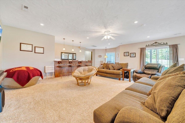 carpeted living room with ceiling fan and a textured ceiling