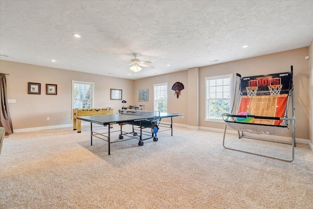 recreation room featuring light colored carpet, a textured ceiling, and ceiling fan