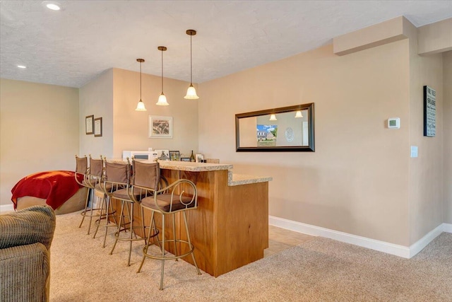 bar featuring hanging light fixtures, light carpet, and a textured ceiling