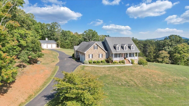 cape cod house featuring an outbuilding, a porch, a garage, and a front lawn