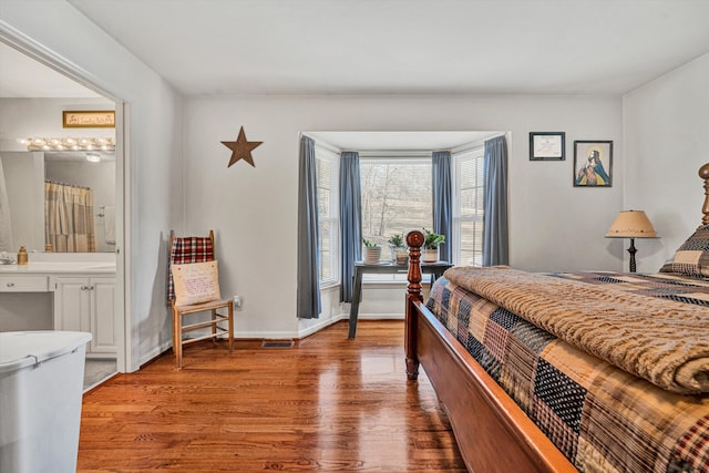 bedroom with wood-type flooring and connected bathroom