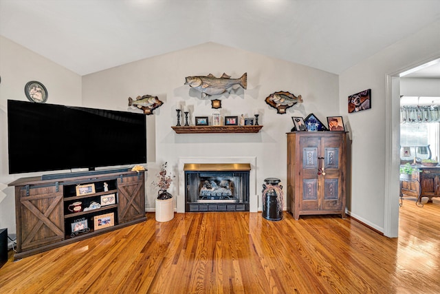 living room featuring lofted ceiling and light hardwood / wood-style floors