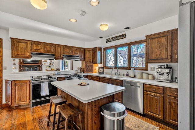 kitchen with sink, a breakfast bar area, stainless steel appliances, a kitchen island, and dark hardwood / wood-style flooring