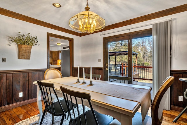 dining space featuring wood walls, a notable chandelier, and light hardwood / wood-style flooring