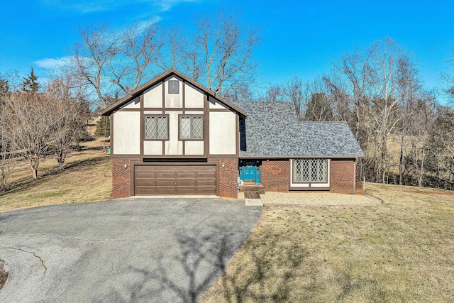 tudor-style house featuring aphalt driveway, a front yard, and brick siding