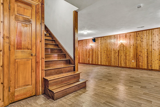 stairs featuring wood-type flooring and wood walls