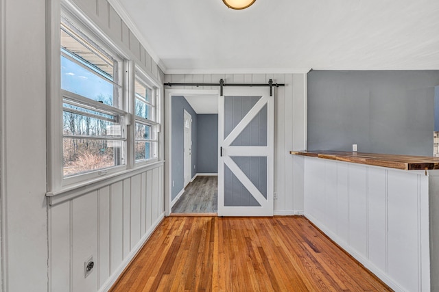 interior space with ornamental molding, a barn door, and light hardwood / wood-style floors