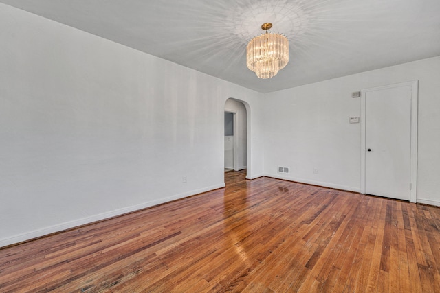 spare room with wood-type flooring and a notable chandelier