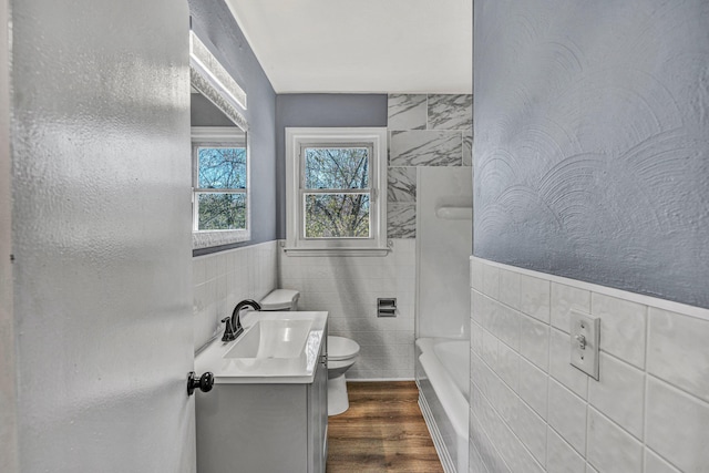 bathroom featuring vanity, toilet, hardwood / wood-style floors, and tile walls