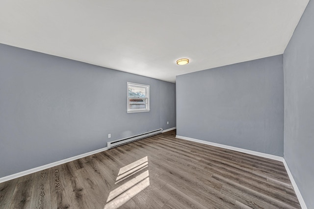 empty room featuring a baseboard heating unit and hardwood / wood-style floors