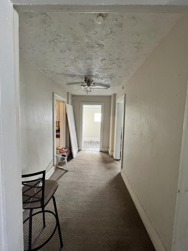 hall featuring a textured ceiling and carpet flooring