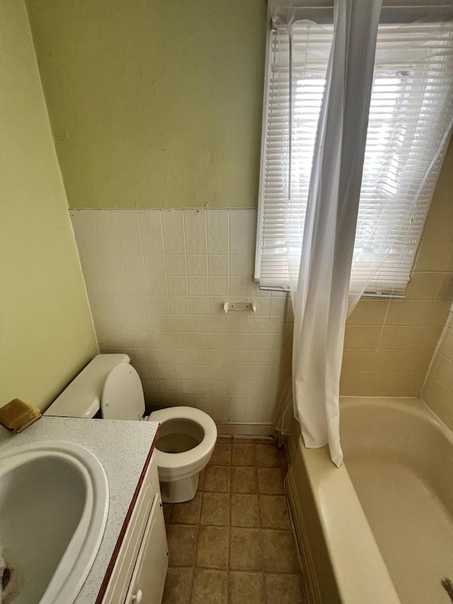 full bathroom with vanity, toilet, tile walls, and a wealth of natural light