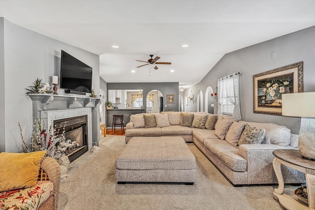 living room with ceiling fan, a fireplace, and vaulted ceiling