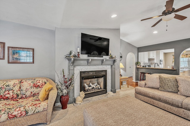 carpeted living room featuring ceiling fan, lofted ceiling, sink, and a tile fireplace