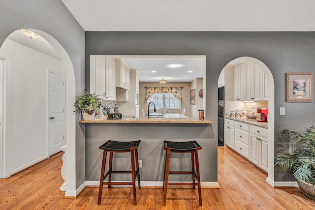 kitchen featuring kitchen peninsula, a breakfast bar area, and white cabinets