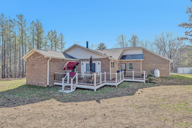 rear view of house with a wooden deck and a lawn