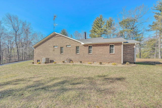 rear view of house with central AC unit and a lawn