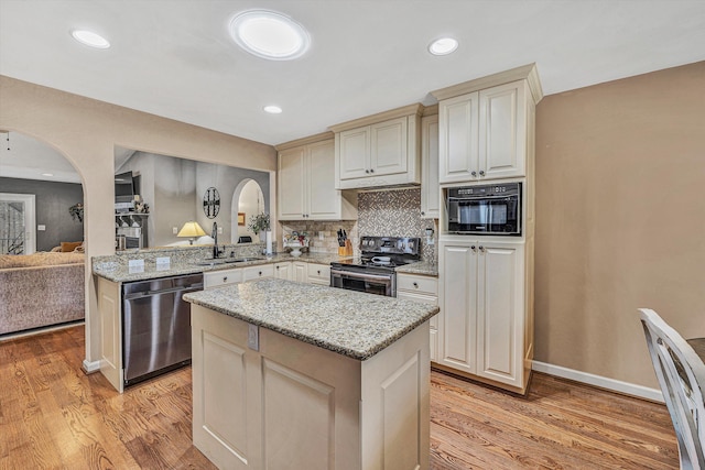 kitchen with sink, appliances with stainless steel finishes, tasteful backsplash, light hardwood / wood-style floors, and kitchen peninsula