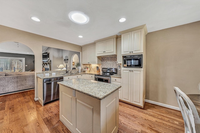 kitchen featuring appliances with stainless steel finishes, kitchen peninsula, light hardwood / wood-style floors, and backsplash