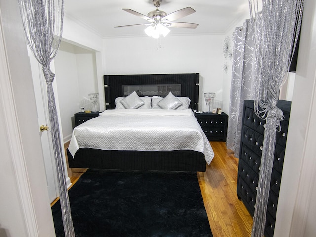 bedroom with hardwood / wood-style floors, crown molding, and ceiling fan