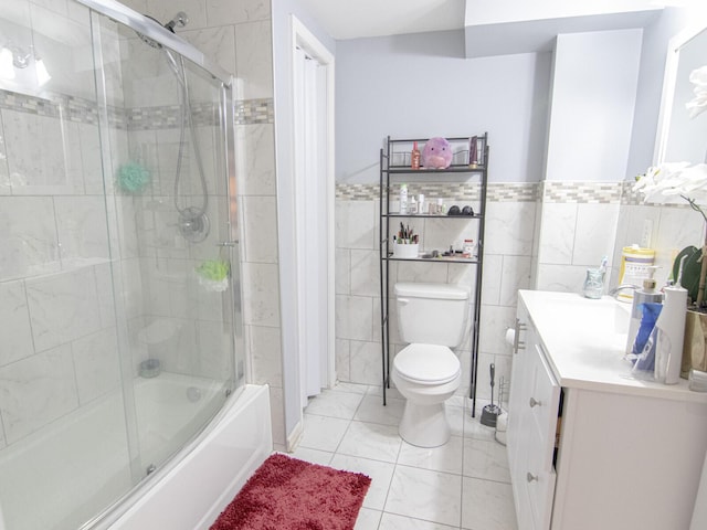 full bathroom with toilet, vanity, bath / shower combo with glass door, and tile walls