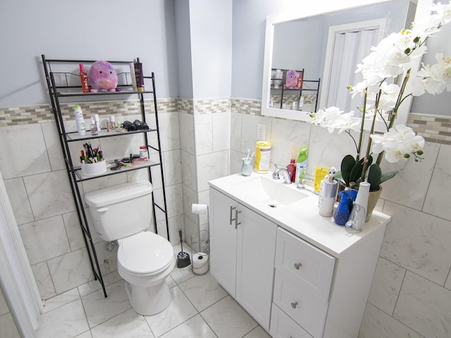 bathroom featuring vanity, toilet, and tile walls