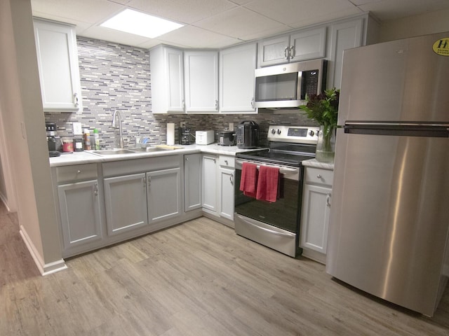 kitchen featuring appliances with stainless steel finishes, sink, light hardwood / wood-style flooring, and backsplash