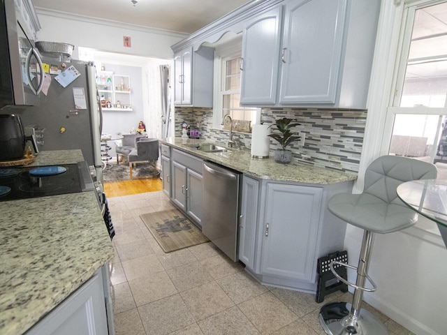 kitchen with sink, light stone counters, appliances with stainless steel finishes, gray cabinets, and decorative backsplash