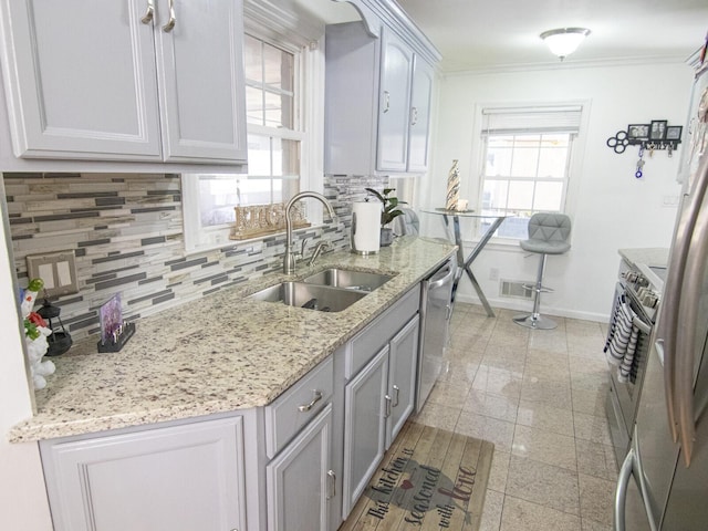 kitchen featuring sink, decorative backsplash, ornamental molding, stainless steel dishwasher, and light stone counters